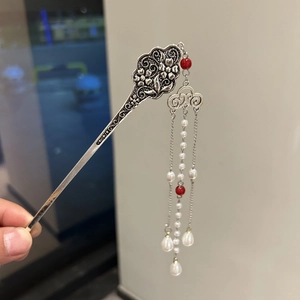 Detail of silver hair stick featuring hollow floral carvings with long pearl and red bead tassels