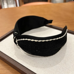 Detail view of black fabric headband with white crochet stitching and textured knot
