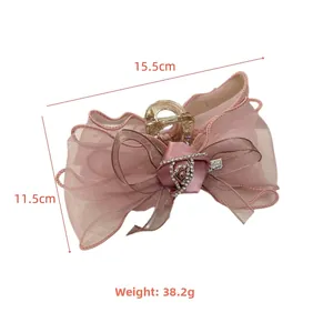 Détail d'une pince à cheveux avec rose en tulle rose, strass et étiquette de 15,5 cm