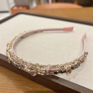 Detail of a pink fabric headband with sparkling crystals and vintage rhinestones