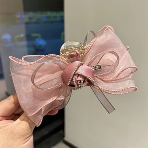 Pince à cheveux avec rose en tulle rose, nœud en satin et strass vue de main levée