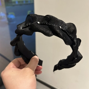 Dettaglio del cerchietto in chiffon nero a pieghe con perline scure ed eleganti perle