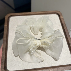 Elegant cream organza bow scrunchie with pearls and ruffled edge on wooden tray