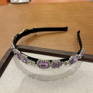 Detailed close-up of sparkling purple crystals and small rhinestones on a slim black headband