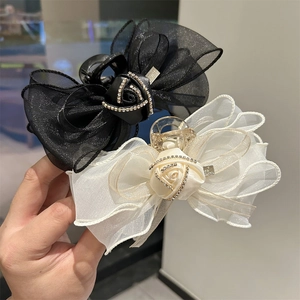 Détail de la pince à cheveux avec nœud en tulle, rose en satin et strass brillants