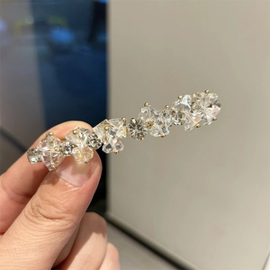 Dettaglio di cristalli geometrici e pietre floreali su un fermaglio per capelli dorato