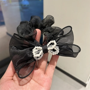 Detail of oversized black sheer mesh scrunchie with sparkling bow and pearl ring