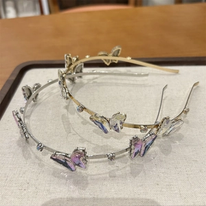 Gros plan de serre-têtes papillon en cristal violet brillant sur plateau en tissu