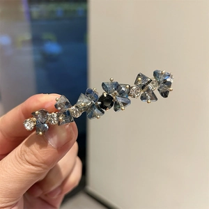Dettaglio molletta per capelli con cristalli blu e trasparenti su montatura dorata