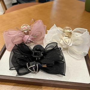 Détail de trois pinces à cheveux en organza avec strass posées sur un plateau