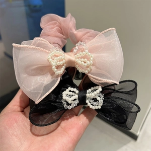 Detail of organza mesh scrunchie with bowknot and faux pearl beaded butterfly ornament