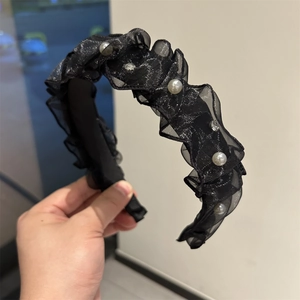 Dettaglio del cerchietto intrecciato nero con volant in rete, perle bianche e strass