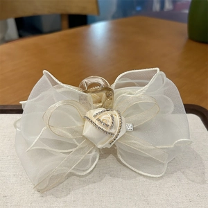 Détail de la pince à cheveux en organza blanc avec rose en satin et petits strass brillants