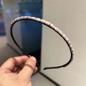 Close-up of handmade square iridescent beads on a slim black headband for women