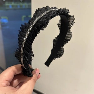 Dettaglio del cerchietto in pizzo nero a pieghe con strass argentati luccicanti