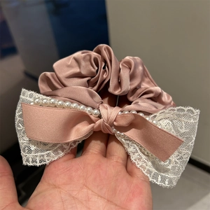 Détails du chouchou en satin rose avec perles blanches et élégant nœud en dentelle