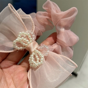 Detailed macro shot of pink mesh bow scrunchie with layered pearls and soft texture