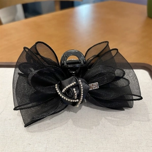 Détail de la pince à cheveux en tulle noir avec rose en strass et étiquette en métal
