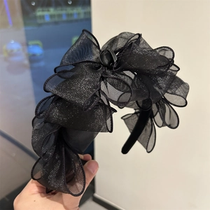 Dettaglio di un cerchietto in rete nera con paillettes e design a fiocco multistrato