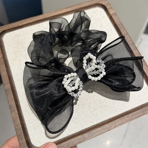 Detailed macro shot of the black mesh bow hair tie with pearl heart center buckle