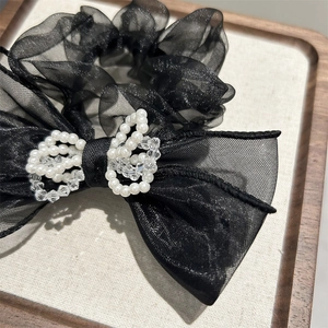 Close-up of black mesh scrunchie featuring elegant pearl and crystal bow decoration