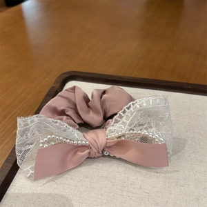 Détail du chouchou en satin rose poudré avec dentelle, perles et nœud ruban