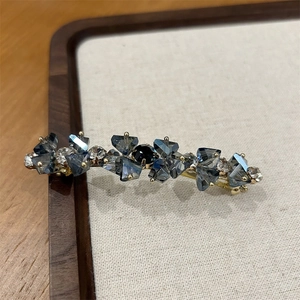 Dettaglio di un fermaglio dorato con cristalli blu e pietra preziosa nera centrale