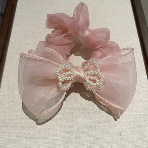 Detailed macro view of pink organza bow hair tie with elegant pearl heart ornament