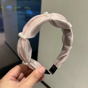 Detail of pink satin headband featuring woven pearl clusters and non-slip protective ends