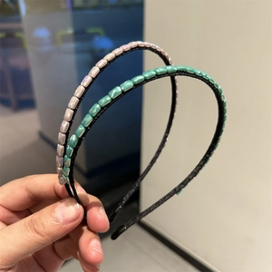 Detail of handmade beaded headbands with shimmering rectangular gemstones in pink and green