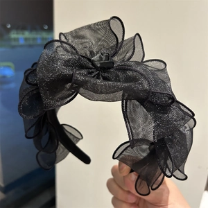 Dettaglio del cerchietto in rete nera con fiori plissettati e trama scintillante fine