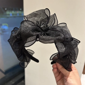 Dettaglio del grande fiocco in rete nera plissettata su un cerchietto alla moda