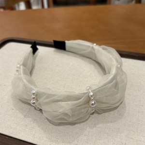 Detail of white gauze headband with woven pearl embellishments and soft pleated fabric texture