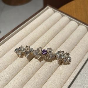 Dettaglio di un fermaglio dorato con cristalli trasparenti e pietra viola centrale