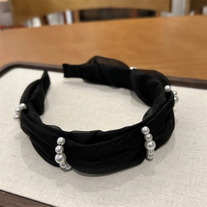 Close-up of black satin headband with elegant pearl accents and pleated texture detail