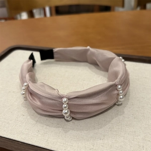 Detail of champagne pleated silk headband featuring elegant white pearls and soft texture
