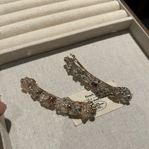 Dettagli di due fermagli per capelli in cristallo francese con pietre lucide su lega dorata
