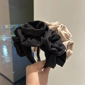 Close-up of handmade rose fabric headband featuring layered floral texture in black and beige
