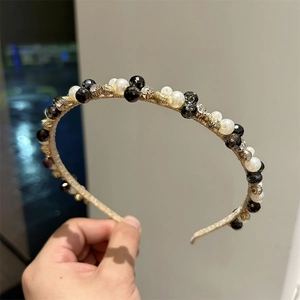 Close-up of handmade headband featuring white pearls, black faceted beads and gold accents