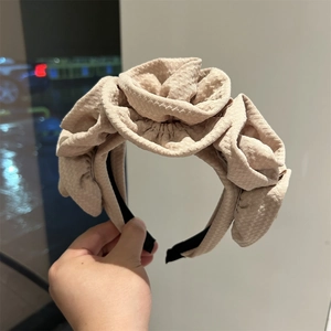 Close-up of beige fabric headband featuring three large 3D pleated rose flower decorations