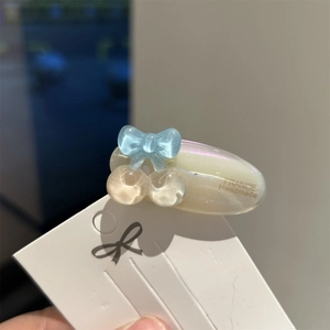Detail of a handmade acetate hair clip with cherry and bow accents on a pink base