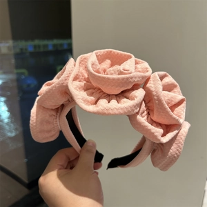 Detailed close-up of pink fabric headband featuring three large handmade rose floral ornaments