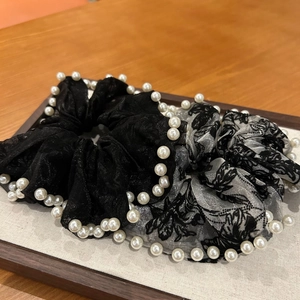 Détail de deux chouchous en dentelle avec perles blanches et motifs floraux rétro