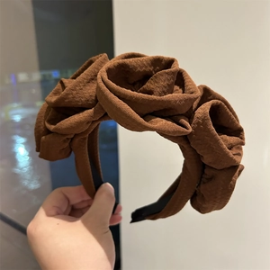 Detailed close-up of brown fabric headband with handmade 3D rose flower decorations