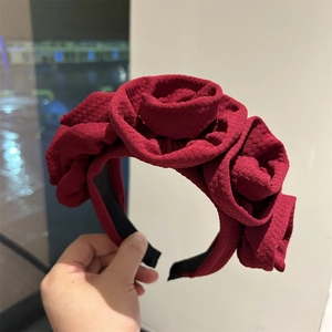 Detailed view of large burgundy fabric rose headband with 3D floral texture for gala
