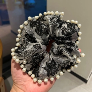 Gros plan du chouchou à fleurs roses noires avec bordure en perles et fini métallisé