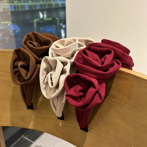 Detailed view of handmade fabric rose headbands in brown, cream, and red colors