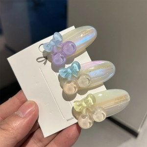 Close-up of three handmade acetate cherry hair clips with pearlescent finish on card