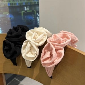 Detailed view of handmade fabric rose headbands in black, cream, and pink on a chair