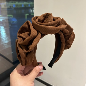 Detail of dark brown handmade fabric roses on a wide headband with textured petals